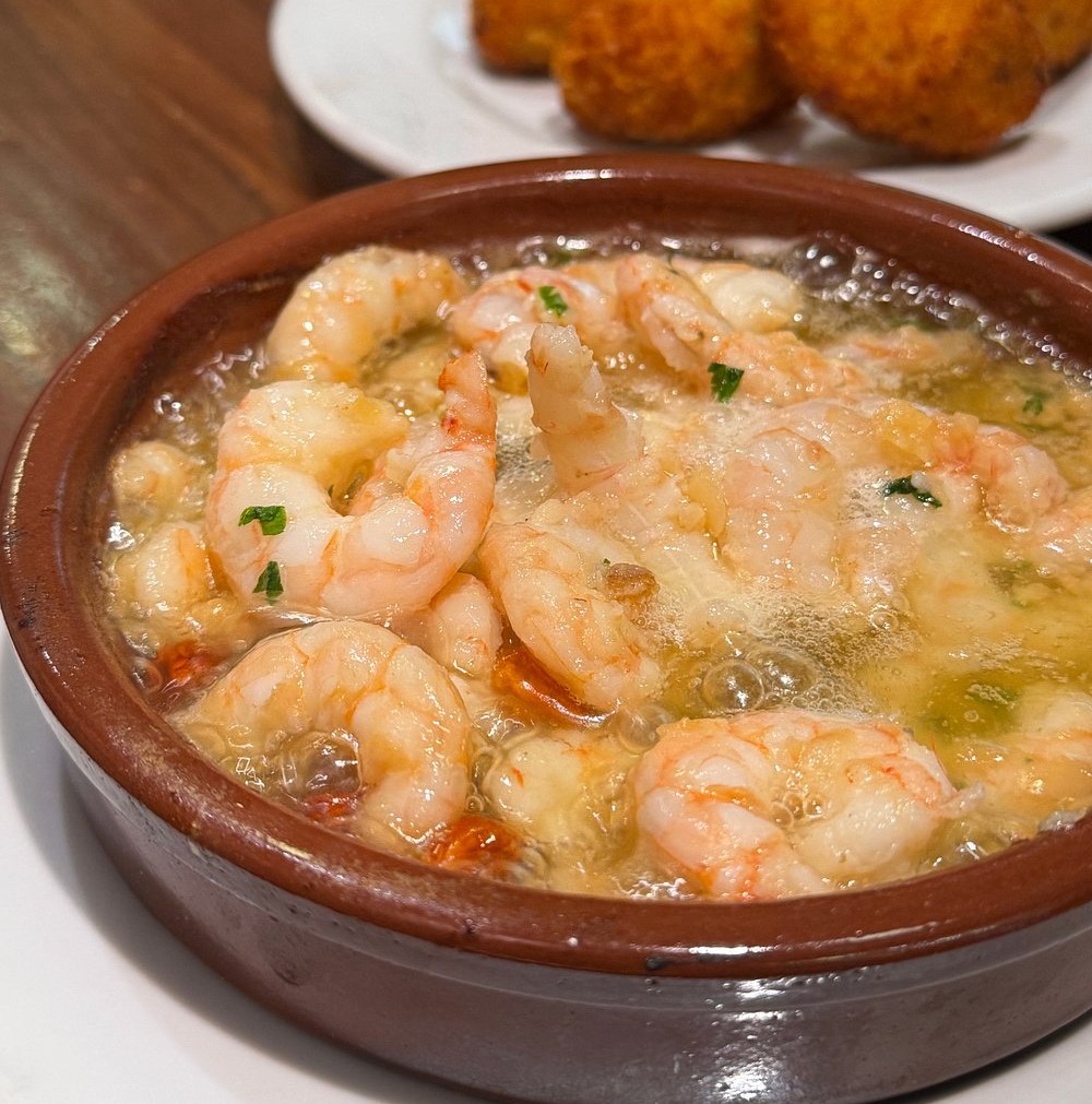 Spanish Garlic Prawns (Gambas al Ajillo) sizzling in olive oil, garlic, and chili at La Casa Del Abuelo, Madrid – a must-try Spanish delicacy.